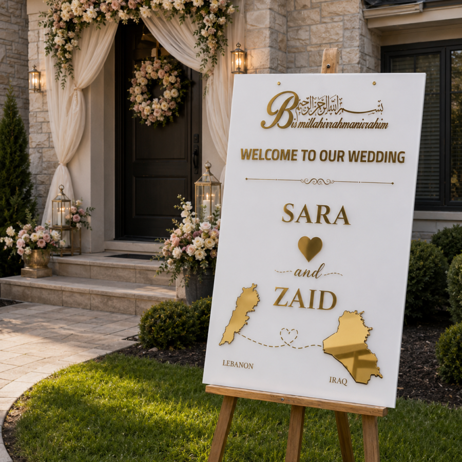 Personalized white acrylic wedding welcome sign with gold mirror Lebanon and Iraq maps displayed on an easel by a decorated Canadian home entrance